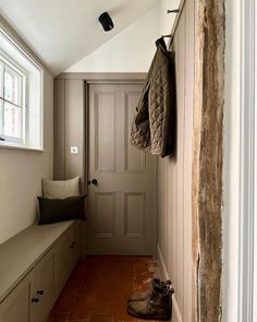 a hallway with a bench, coat rack and window