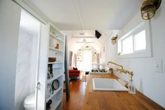 a long narrow kitchen with wood floors and white walls, along with an open door leading to the living room