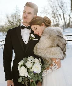 a bride and groom standing in the snow