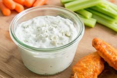 carrots and celery sticks with dip in a glass jar on a cutting board