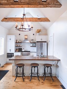 a kitchen with three stools and a center island in the middle of the room