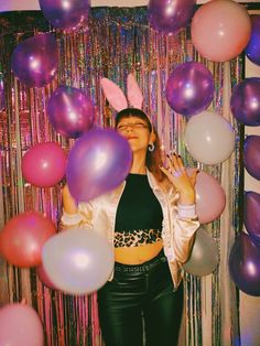 a woman standing in front of balloons and streamers