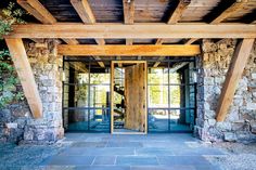 an entrance to a stone building with wooden beams and glass doors that lead into the outside