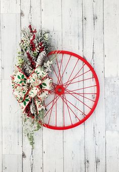 a bicycle wheel decorated with pine cones and evergreens on a white wooden background for christmas