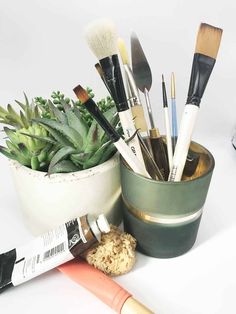 a cup filled with lots of brushes next to a brush holder on top of a table