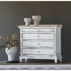 two white vases sitting on top of a dresser