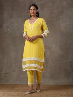 A two piece set comprising of a sunshine yellow kurta with pants. Curated in premium soft cotton, the kurta has lace detailing on the neck,hem and sleeves. Paired with straight cut soft cotton pants adding a slight organza touch to it ,it is finished with lace detailing. Color: Yellow Fabric Composition: Soft cotton Note: The product will be delivered within20-25 days of order placed Care Instruction: Dry Clean Only. Do not use heavy Iron Cotton Salwar Kameez With Lace Work And Long Sleeves, Cotton Lace Work Sets With Long Sleeves, Long Sleeve Cotton Sets With Lace Work, Yellow Cotton Palazzo Set For Navratri, Navratri Yellow Cotton Palazzo Set, Spring Cotton Salwar Kameez With Lace Work, Yellow Sets With Gota Work For Spring, Spring Yellow Sets With Gota Work, Yellow Cotton Palazzo Set With Gota Work