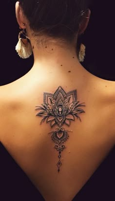 the back of a woman's neck with an intricate tattoo design on her lower back