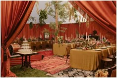 a dining room with tables and chairs covered in orange draping, surrounded by red curtains