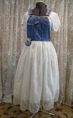 a white dress on a mannequin stand in front of curtains