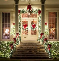 christmas lights decorate the front steps of a house with wreaths and bows on it