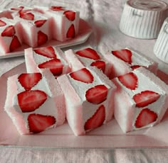 strawberry shortbreads with white frosting and sliced strawberries on the top, sitting on a pink plate