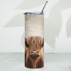 a close up of a travel mug with a cow on it's side and a straw sticking out of its mouth