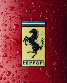 the ferrari logo is shown on a red car with water droplets around it and there are other cars in the background