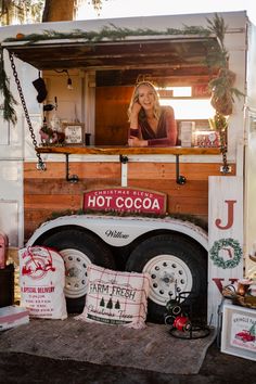 a woman sitting in the back of a food truck with christmas decorations on it's side