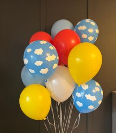 a bunch of balloons with clouds on them are in a vase next to a wall