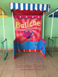 a carnival booth is set up in the middle of a tiled floored area with blue and white striped awnings