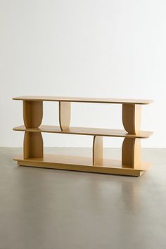 a wooden shelf sitting on top of a floor next to a white wall with two shelves