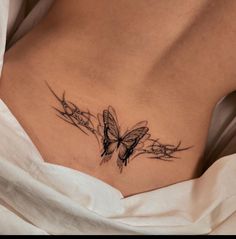 a woman's stomach with a butterfly tattoo on her side and flowers in the back