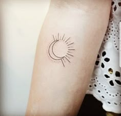 a woman's arm with a small sun and moon tattoo on the left forearm