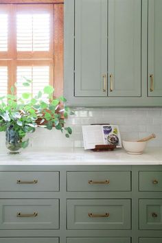 a kitchen with green cabinets and white counter tops