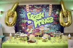 a table topped with lots of desserts and balloons in front of a brick wall