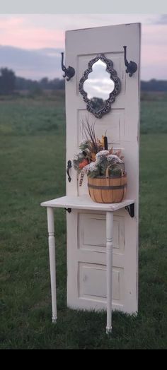 an old door is decorated with plants and a basket on it's side table