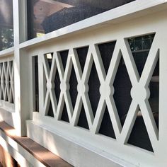 a wooden bench sitting on top of a white wall next to a window with lattices