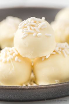 some white chocolates with sprinkles on top in a black bowl, ready to be eaten