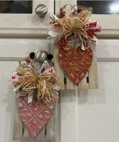 two hearts are hanging on the front door with burlocks and ribbons attached to them