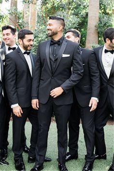 a group of men in tuxedos standing next to each other on the grass