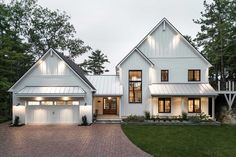 a large white house with two garages on the front and one story, surrounded by trees