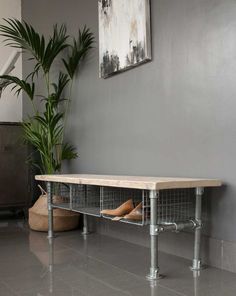 a wooden bench sitting next to a potted plant on top of a hard wood floor