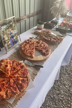 several pizzas on wooden platters sitting on a table in front of a window