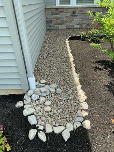 a rock garden bed in front of a house with gravel and rocks on the ground