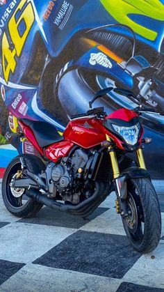 a red and black motorcycle parked in front of a wall with colorful graphics on it