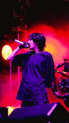 a male in a black shirt is on stage with a microphone and lights behind him