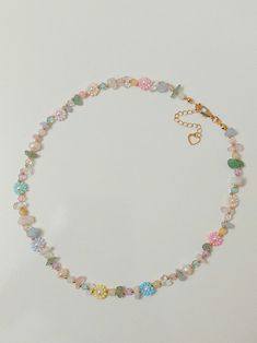 a necklace with various colored beads and charms hanging from it's side on a white surface