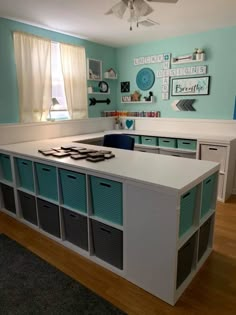 a kitchen with blue walls and white counter tops, drawers on each side and several bins in the middle