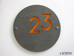 a metal sign with the number twenty three in orange on it's center circle