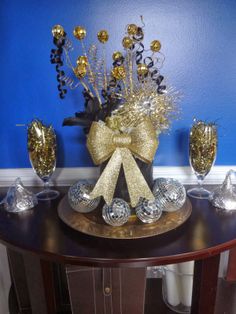 a table with some silver and gold decorations on it's top, along with two wine glasses