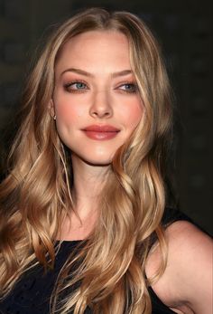 a close up of a woman with long blonde hair and blue eyes wearing a black dress