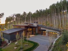 an aerial view of a modern home surrounded by trees in the fall or early autumn