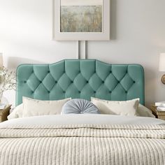 a blue upholstered headboard on a bed with white pillows and throw pillows