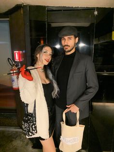 a man and woman standing next to each other in front of a door holding shopping bags