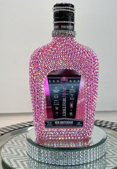 a bottle that is sitting on top of a glass table covered in pink and silver crystals