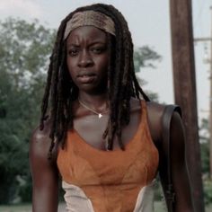 a woman with dreadlocks and an orange top