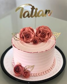 there is a pink cake with roses on it and the name tattan written in gold