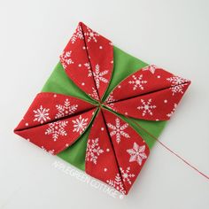 a red and green origami piece with snowflakes on it