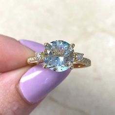 a woman's hand holding an engagement ring with a blue topazte and diamonds